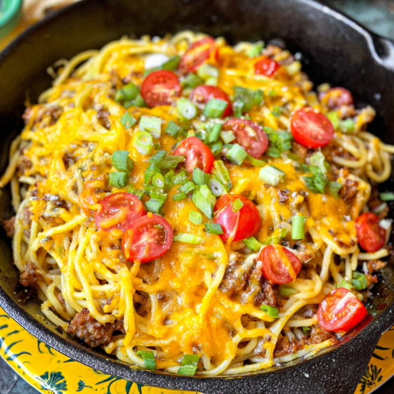 A bowl of spaghetti with tomatoes and cheese.
