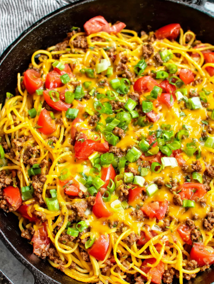 A bowl of food with noodles and tomatoes.