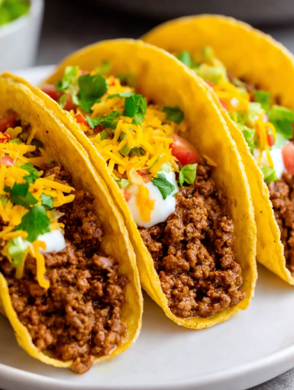A plate of food with two tacos and a bowl of chili.