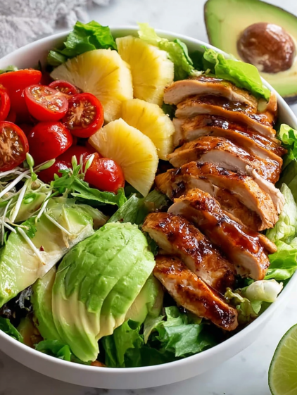 A bowl of food with chicken, tomatoes, avocado, and pineapple.