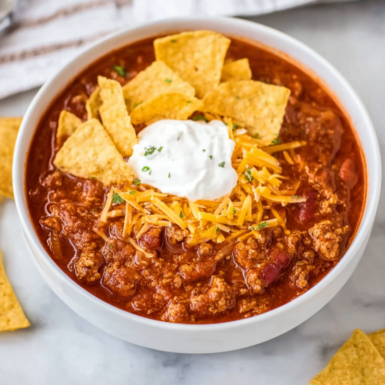 A bowl of chili with chips on top.