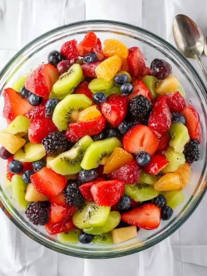 A bowl of fruit salad with kiwi, strawberries, blueberries, and oranges.