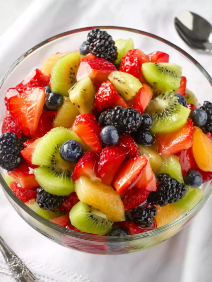 A bowl of fruit salad with kiwi, strawberries, blueberries, and blackberries.