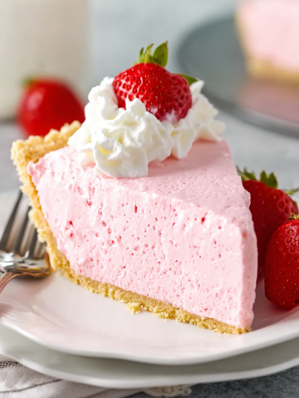 A slice of pink cake with white whipped cream and strawberries.