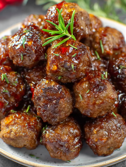 A plate of meatballs with a sprig of parsley on top.