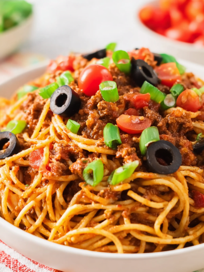 A bowl of spaghetti with tomatoes and olives.
