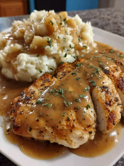 A plate of chicken with gravy and mashed potatoes.
