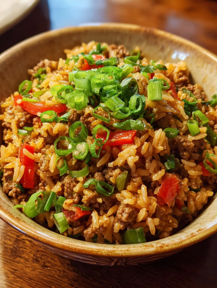 A bowl of rice and meat with green onions on top.