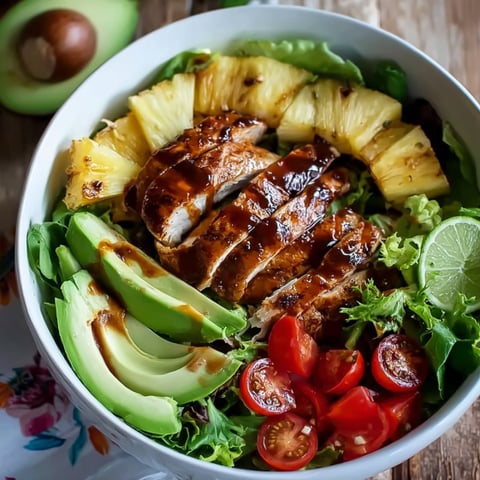 A bowl of chicken salad with pineapple, tomatoes, and avocado.