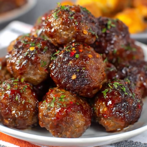 A plate of meatballs covered in a honey garlic sauce.