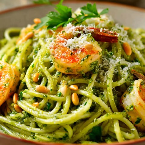 A bowl of pasta with shrimp and pesto.