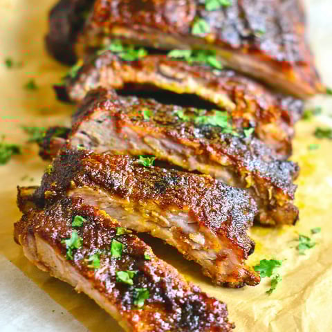 A close up of a pile of ribs on a paper towel.