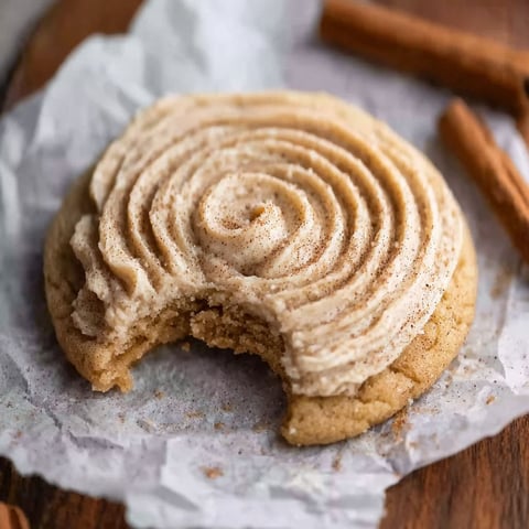 A half eaten cookie with a swirl of frosting.